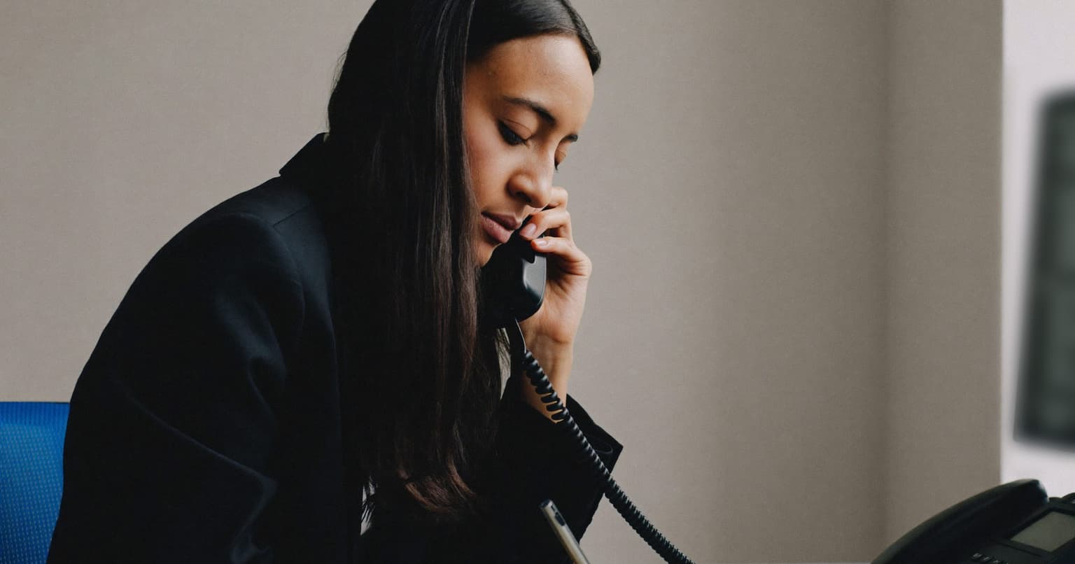 Accounts payable specialist on a desk phone call, following up with a vendor