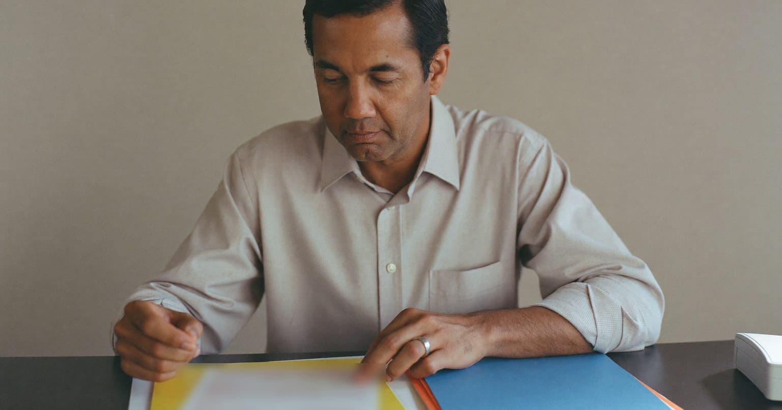 Accounts payable clerk filing vendor paperwork into colored folders at his desk