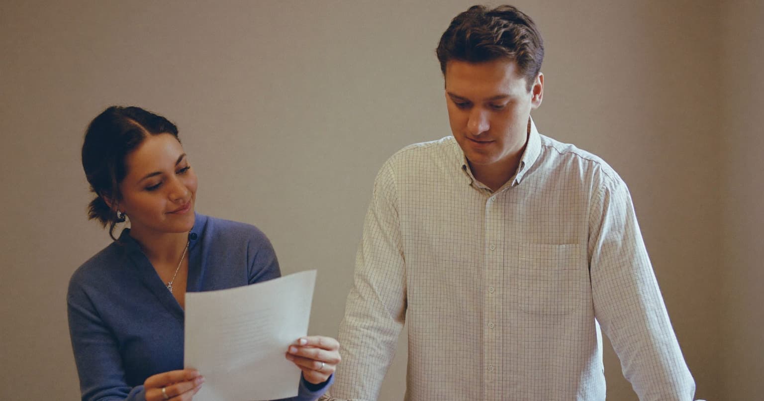 Office manager showing a freelance contractor a paper form at a small office desk